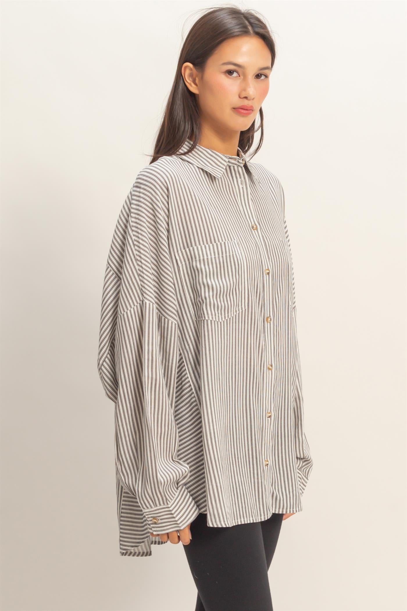 woman wearing a striped oversized button-up shirt with two front pockets and long sleeves, paired with black leggings