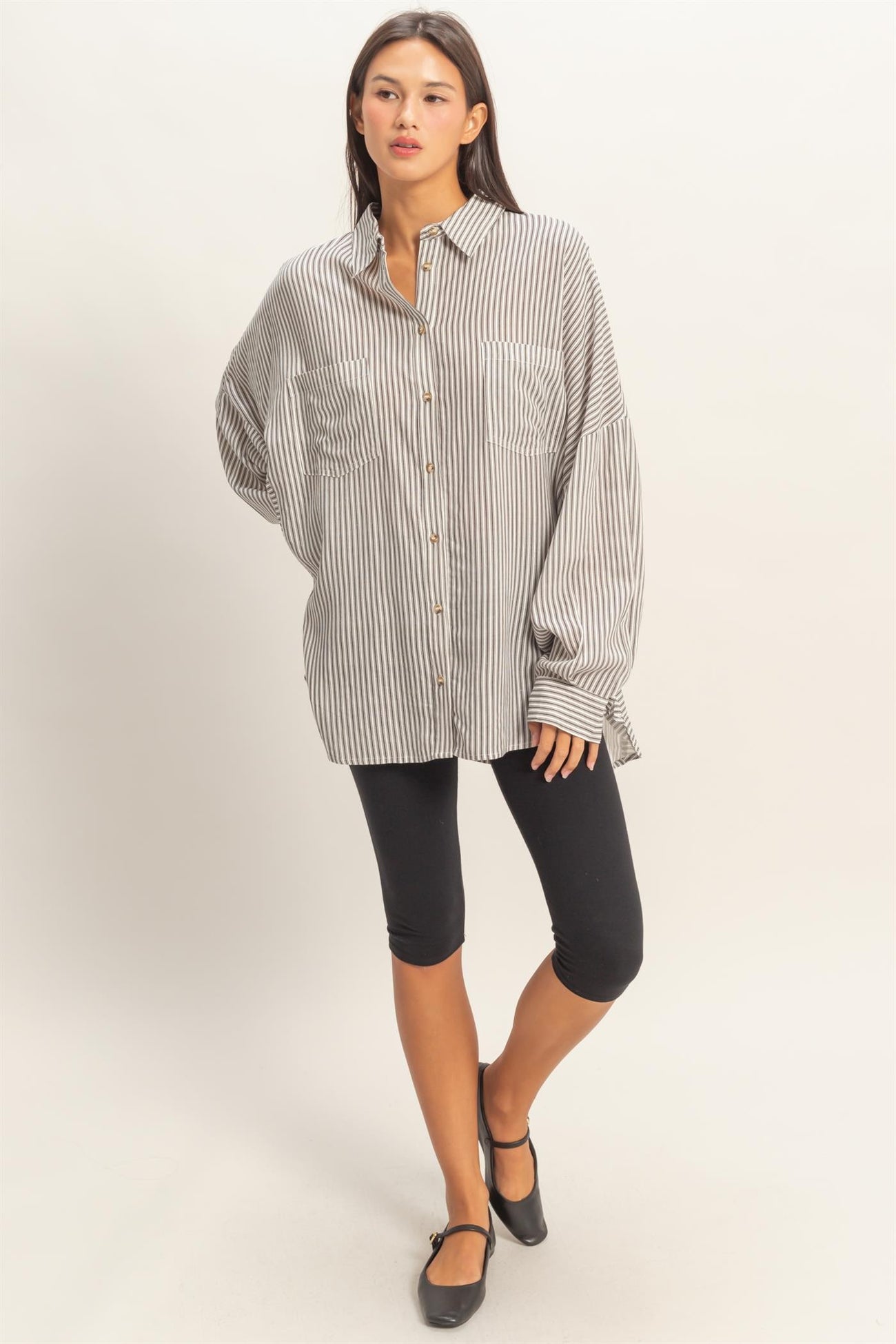 woman wearing a striped oversized button-up shirt with long sleeves and black leggings
