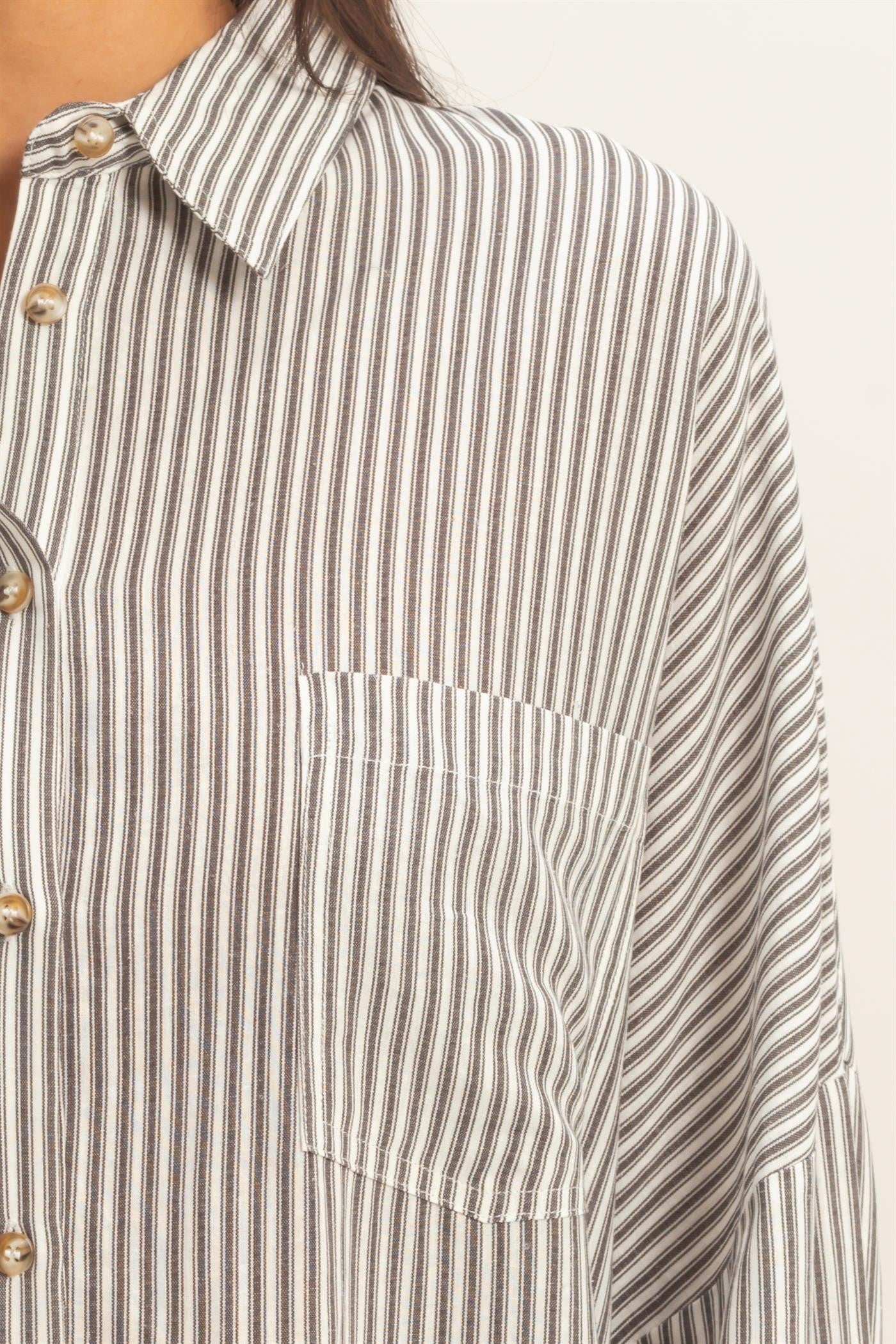 woman wearing a gray and white striped oversized shirt with a front pocket and button details