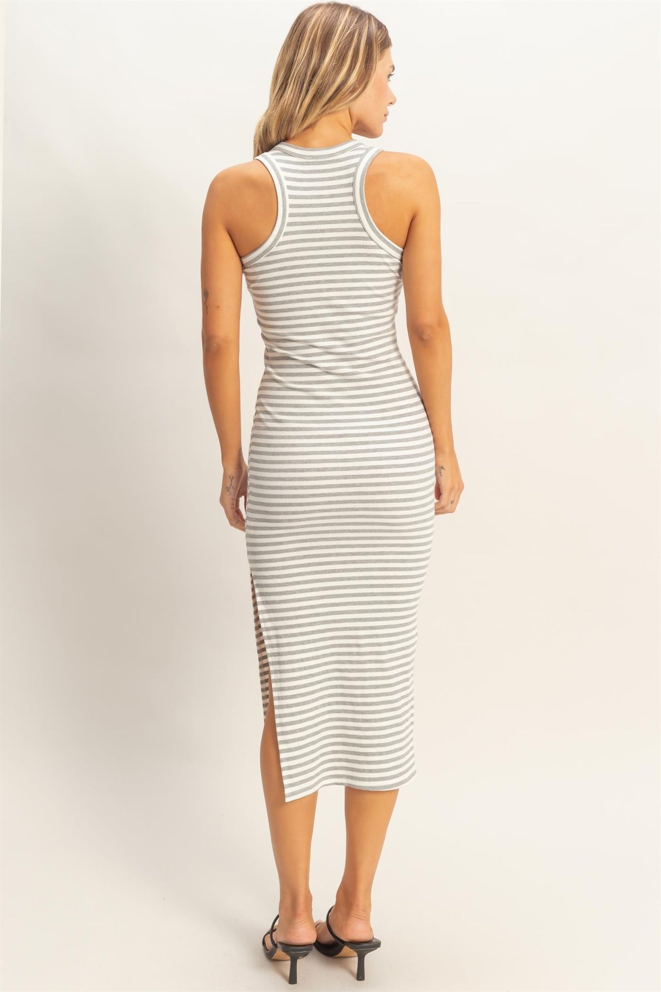 woman wearing a grey and white striped sleeveless midi dress with side slits