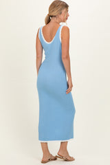 woman wearing a light blue sleeveless maxi dress with scalloped edges and a low back, standing with her back facing the camera