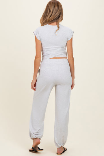 woman wearing a grey maternity crop top with crisscross back and matching jogger pants