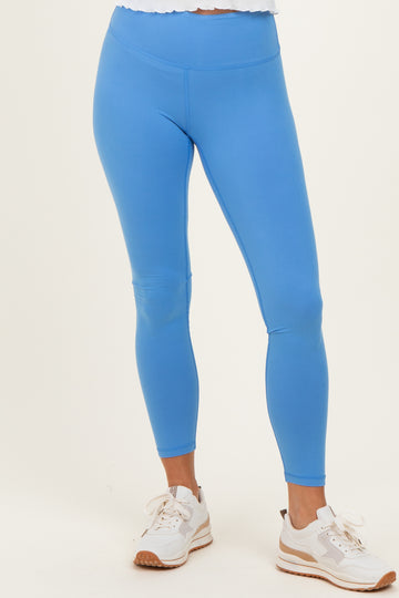 woman wearing bright blue high-waisted leggings with a smooth finish and paired with white sporty shoes