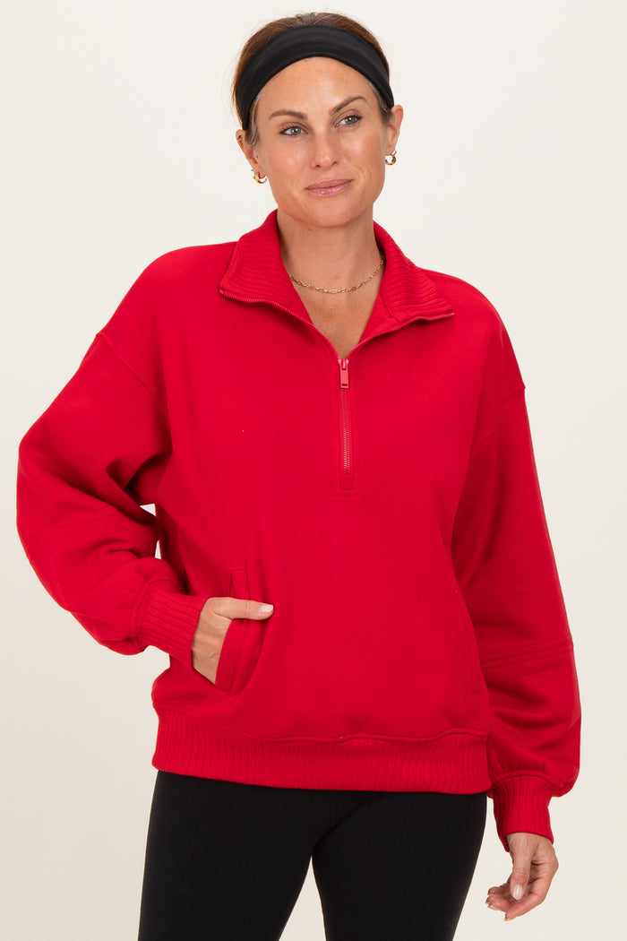 woman wearing a red quarter-zip sweatshirt with side pockets and a relaxed fit