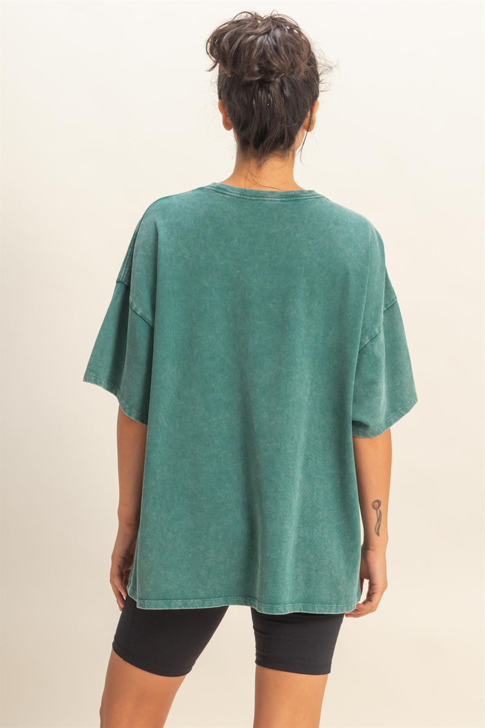 woman wearing an oversized green vintage-style t-shirt and black bike shorts, seen from the back