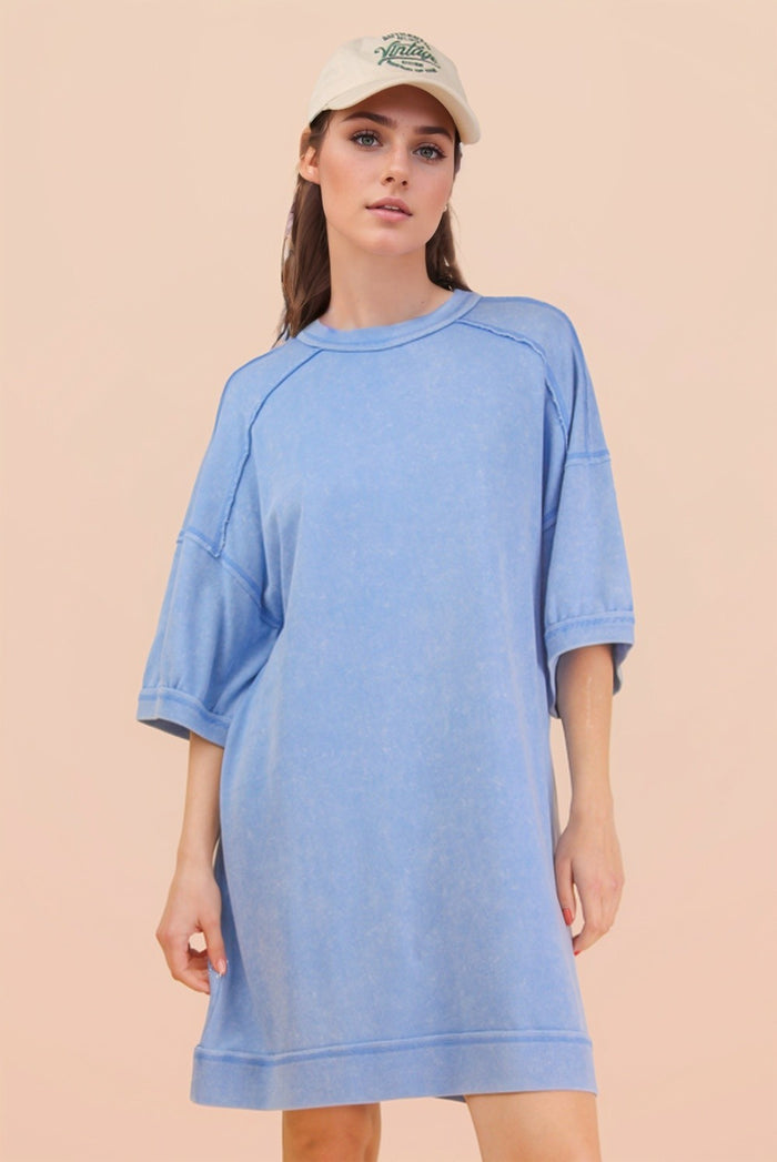 woman wearing a light blue oversized t-shirt dress with short sleeves and a cap