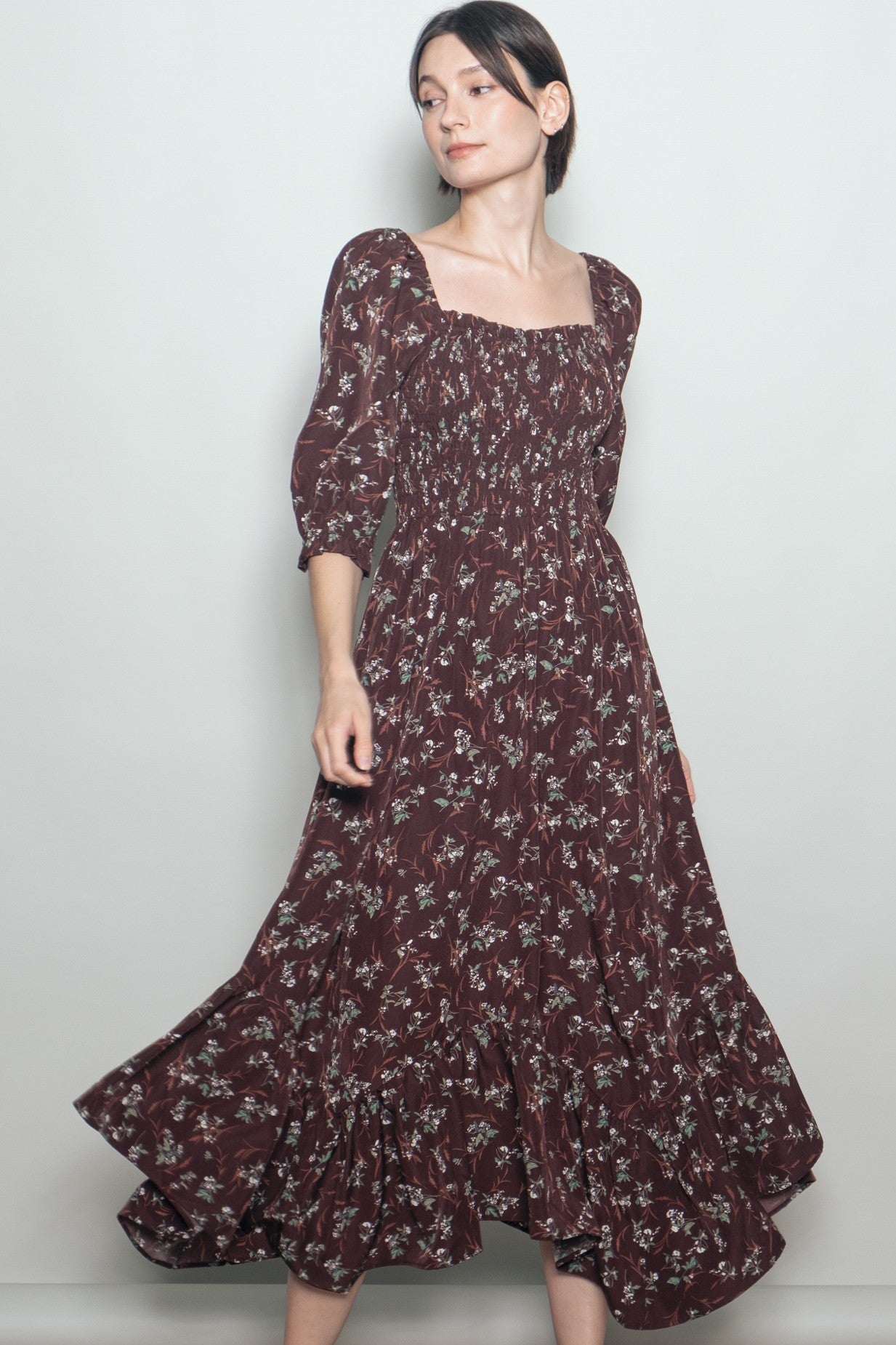 woman wearing a burgundy floral print maxi dress with puff sleeves and a ruffled hem