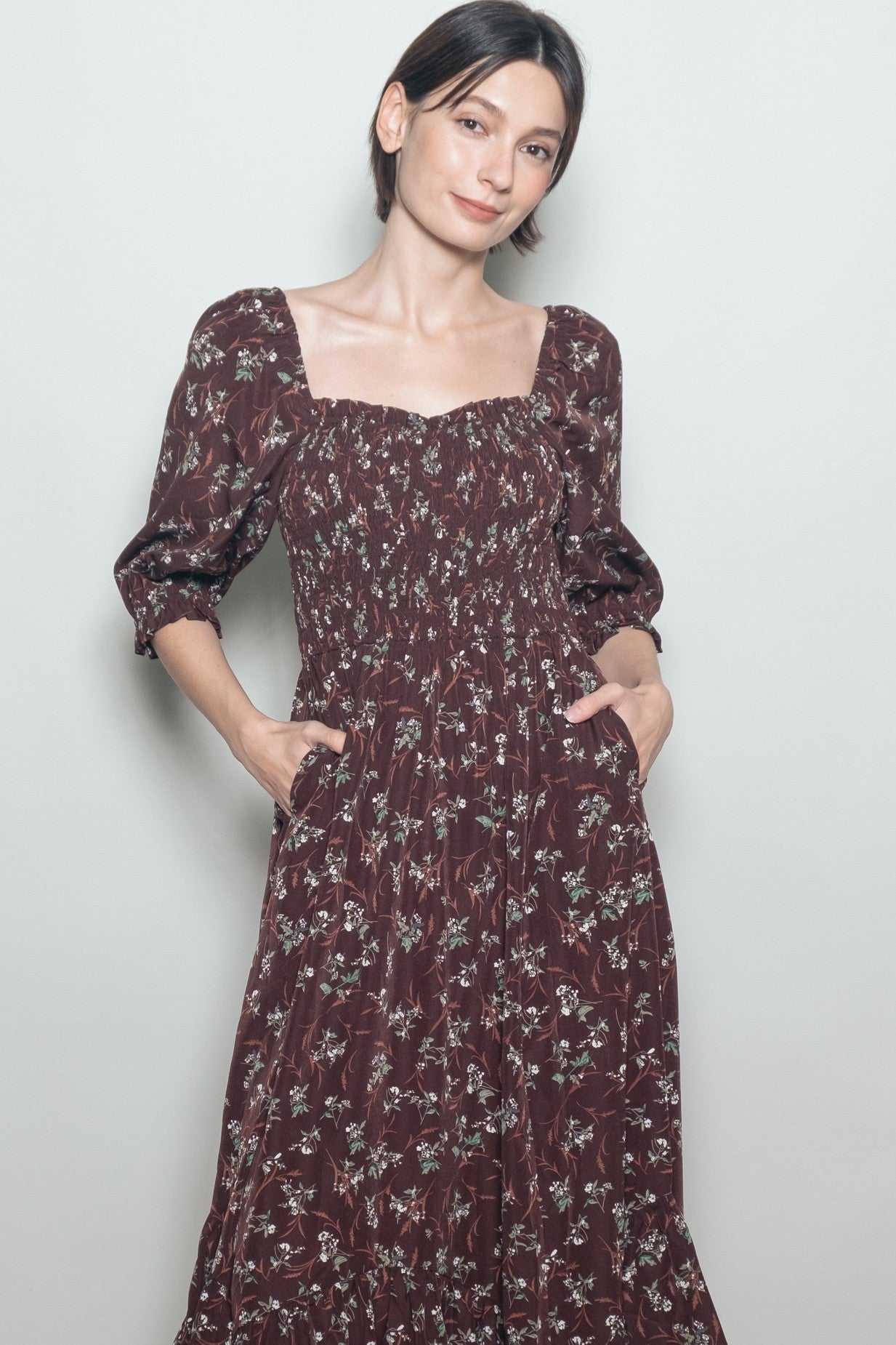 woman wearing a burgundy floral maxi dress with puff sleeves and side pockets