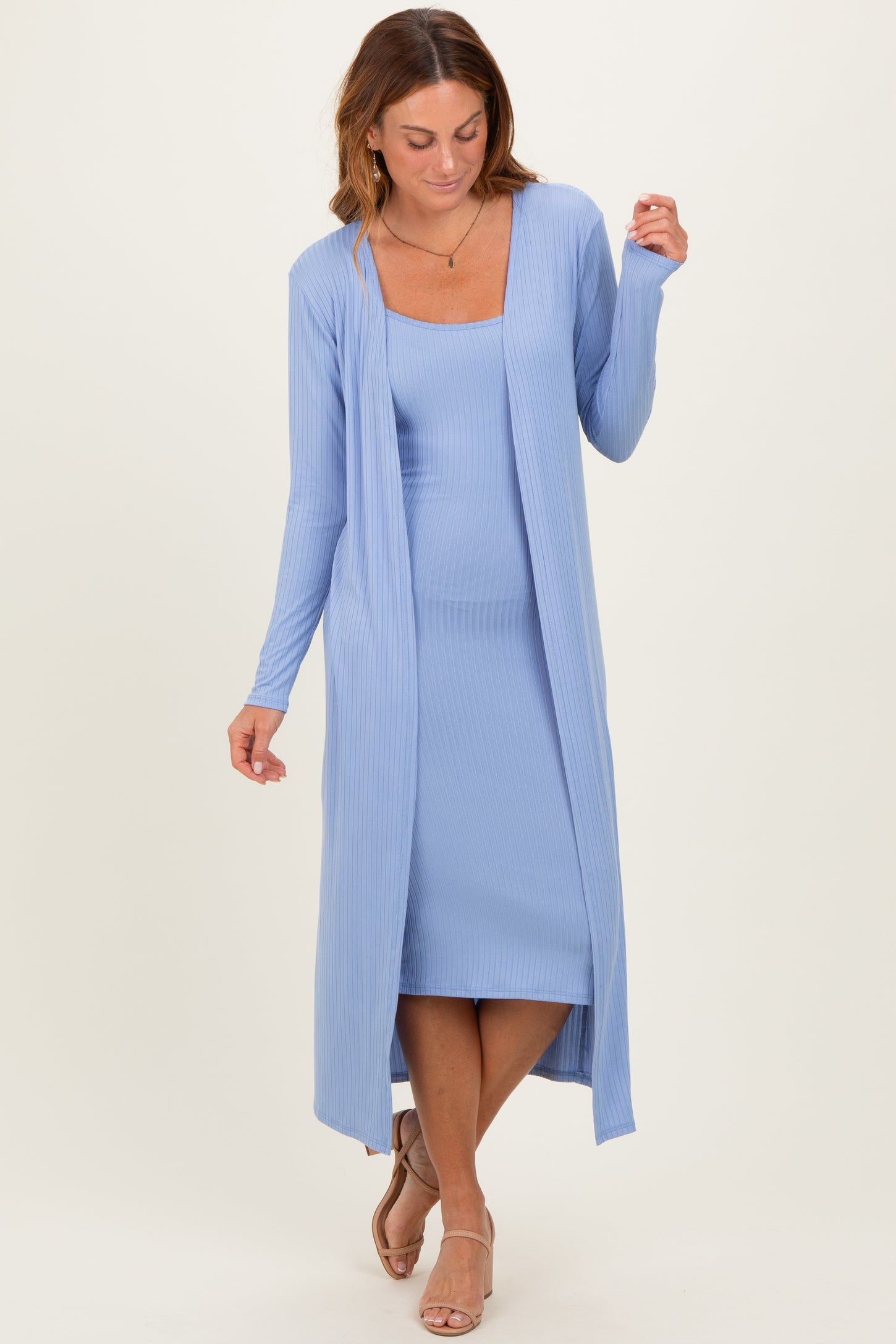 woman wearing a light blue ribbed long cardigan over a matching ribbed dress, styled with sandals