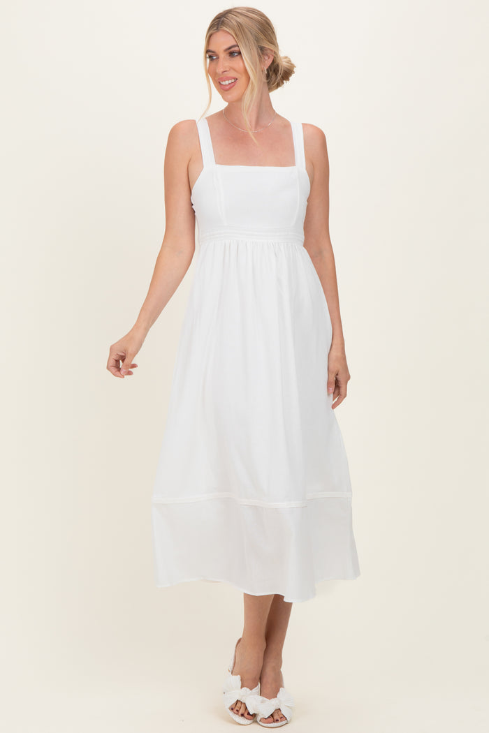 woman wearing a white sleeveless midi dress with a square neckline and tiered hem