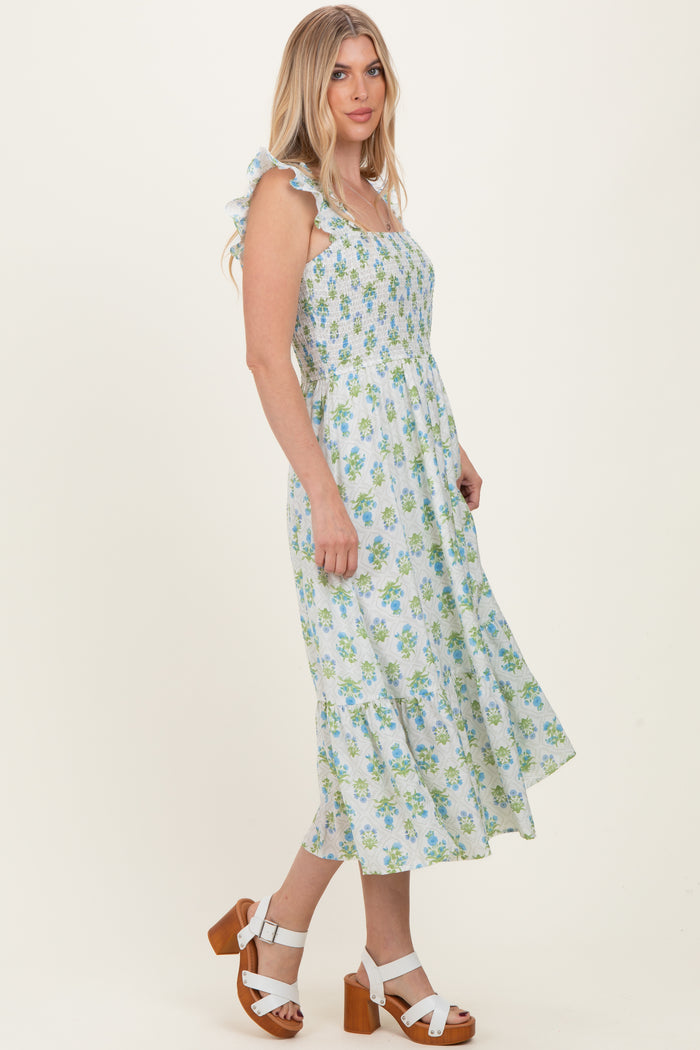 woman wearing a light blue floral print midi dress with ruffle straps and a smocked bodice, paired with heeled sandals