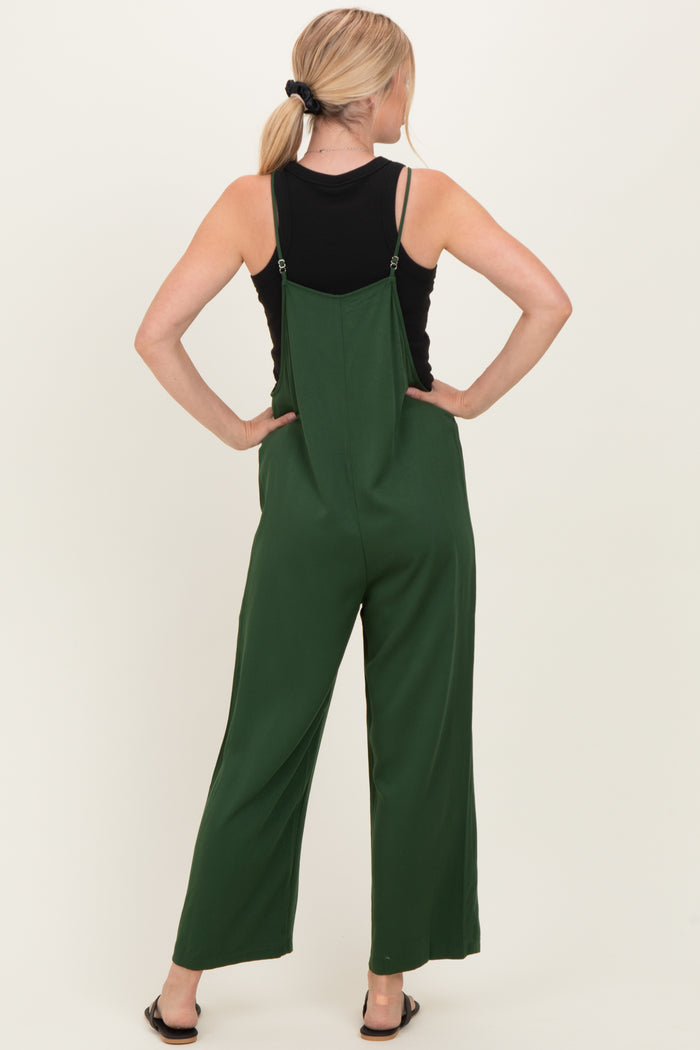 woman wearing a black tank top and green wide-leg jumpsuit, showing the back view with adjustable straps