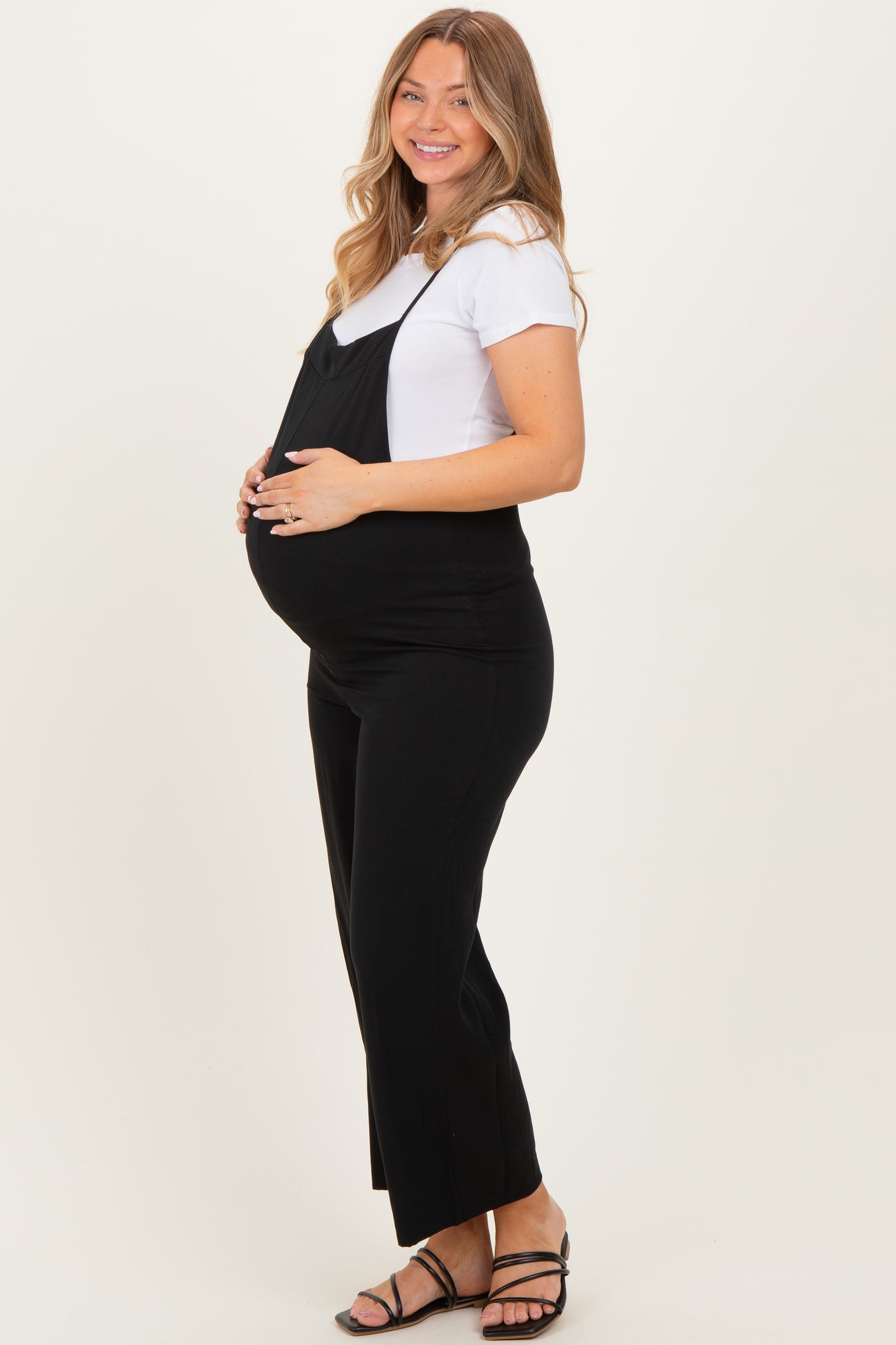 woman wearing a black maternity jumpsuit over a white tee with a visible baby bump