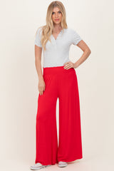 woman wearing a light grey short sleeve henley top and red wide leg pants with an elastic waistband
