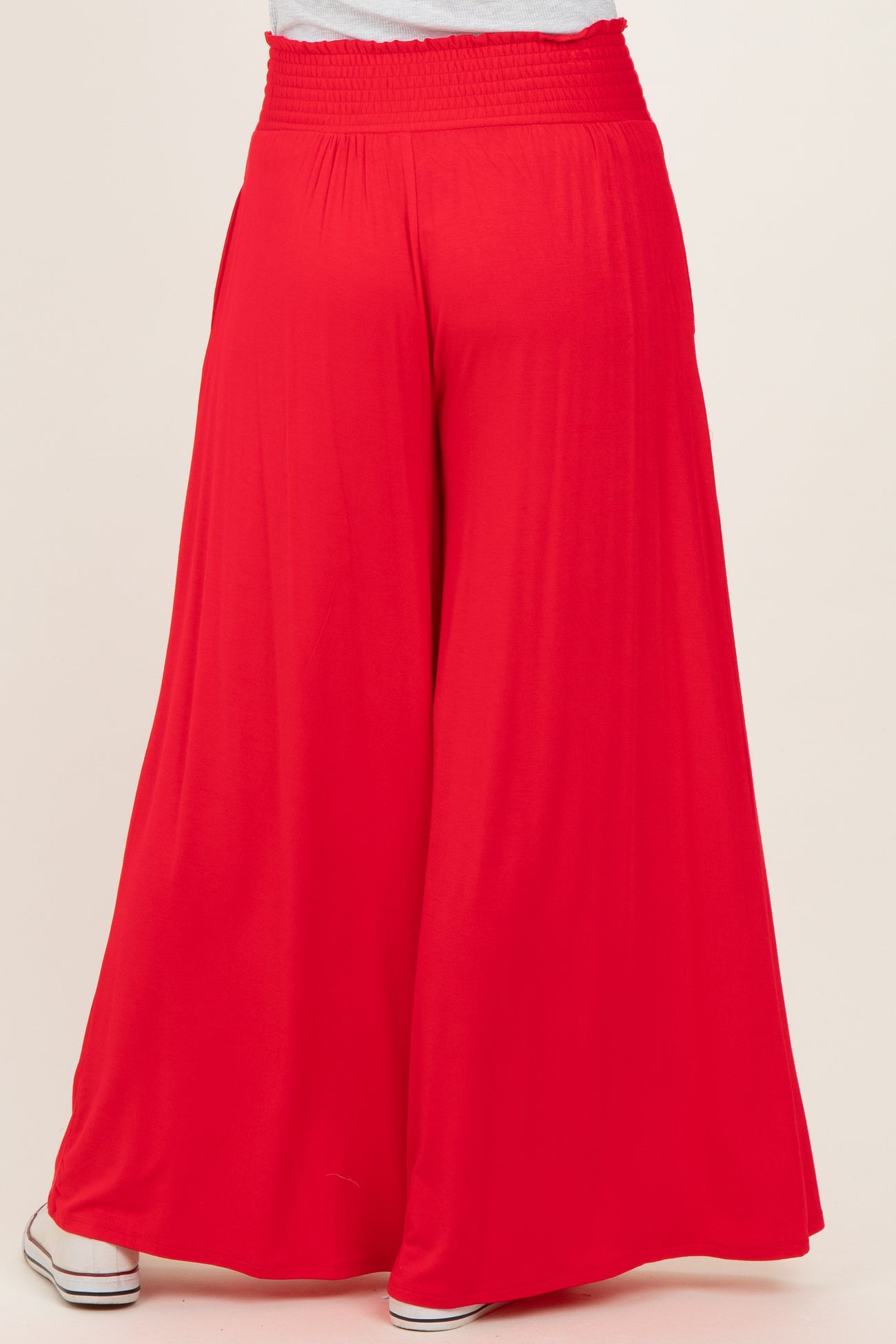 woman wearing red wide-leg pants with a smocked waistband, viewed from the back