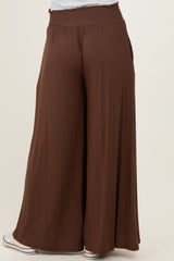 woman wearing brown wide-leg pants with a smocked waistband and a relaxed fit, viewed from the back