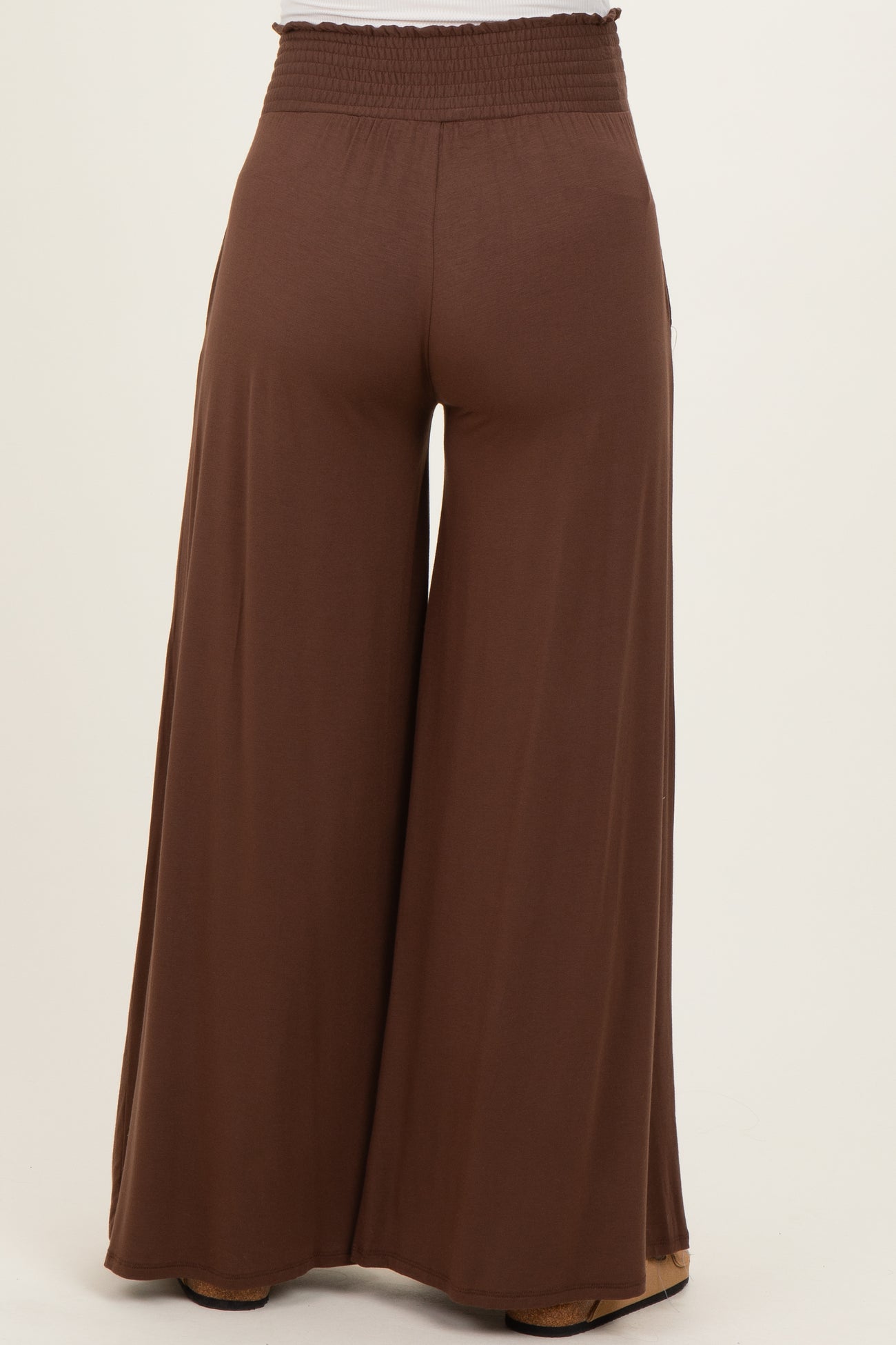 woman wearing brown wide-leg maternity pants with an elastic waistband, viewed from the back