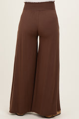 woman wearing brown wide-leg maternity pants with an elastic waistband, viewed from the back