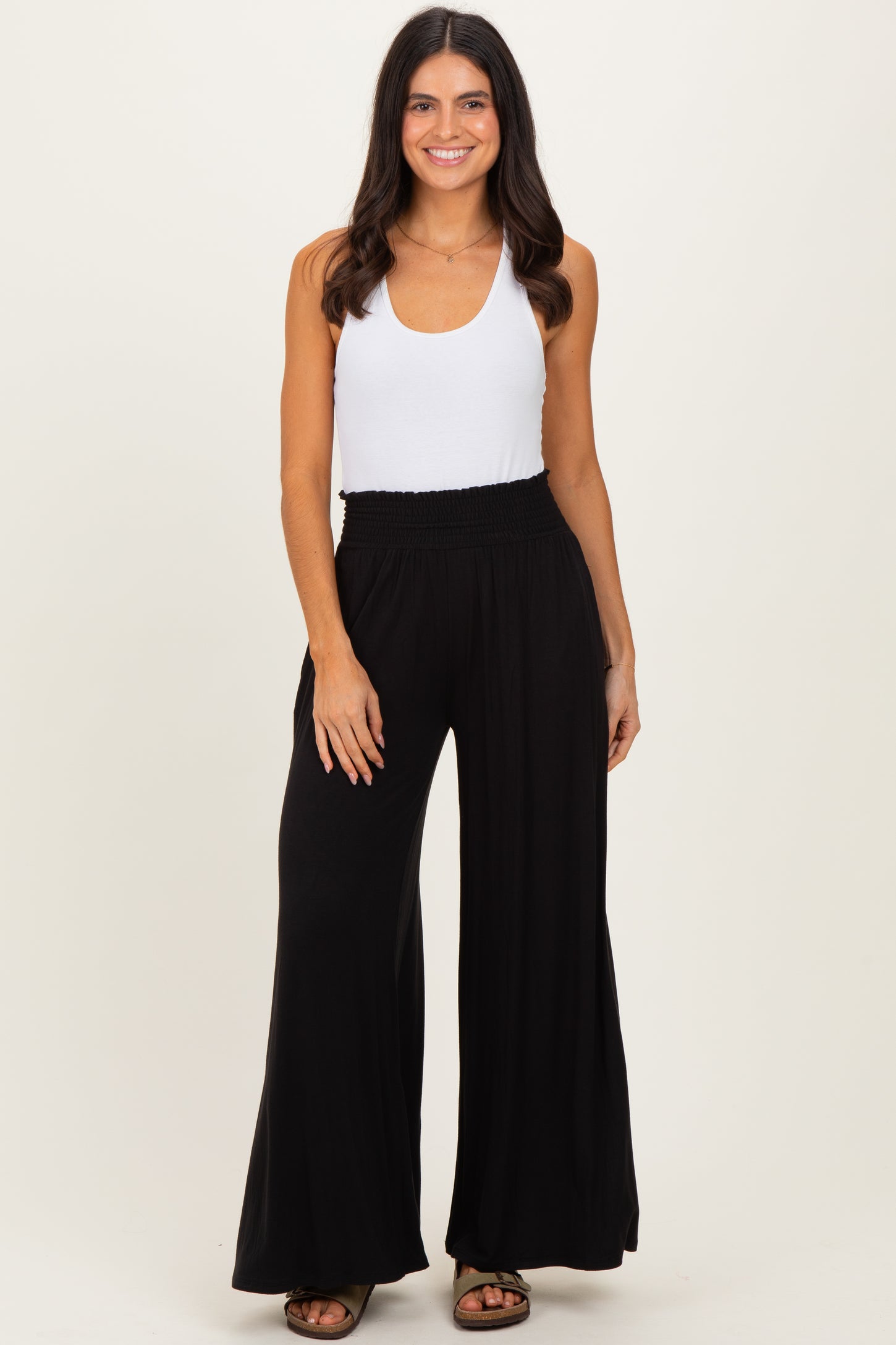 woman wearing a white tank top and black wide-leg pants with a smocked waistband