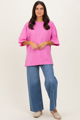 woman wearing an oversized hot pink t-shirt with short sleeves and paired with wide-leg blue jeans