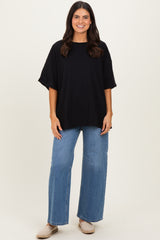 woman wearing a black oversized t-shirt and light blue wide leg jeans with beige slip-on shoes