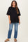 woman wearing a black oversized maternity t-shirt and distressed light blue jeans with a visible baby bump