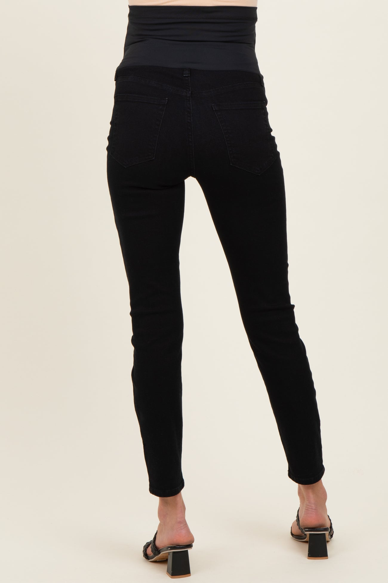 woman wearing black maternity skinny jeans with a high waistband and a fitted silhouette, showing the back view