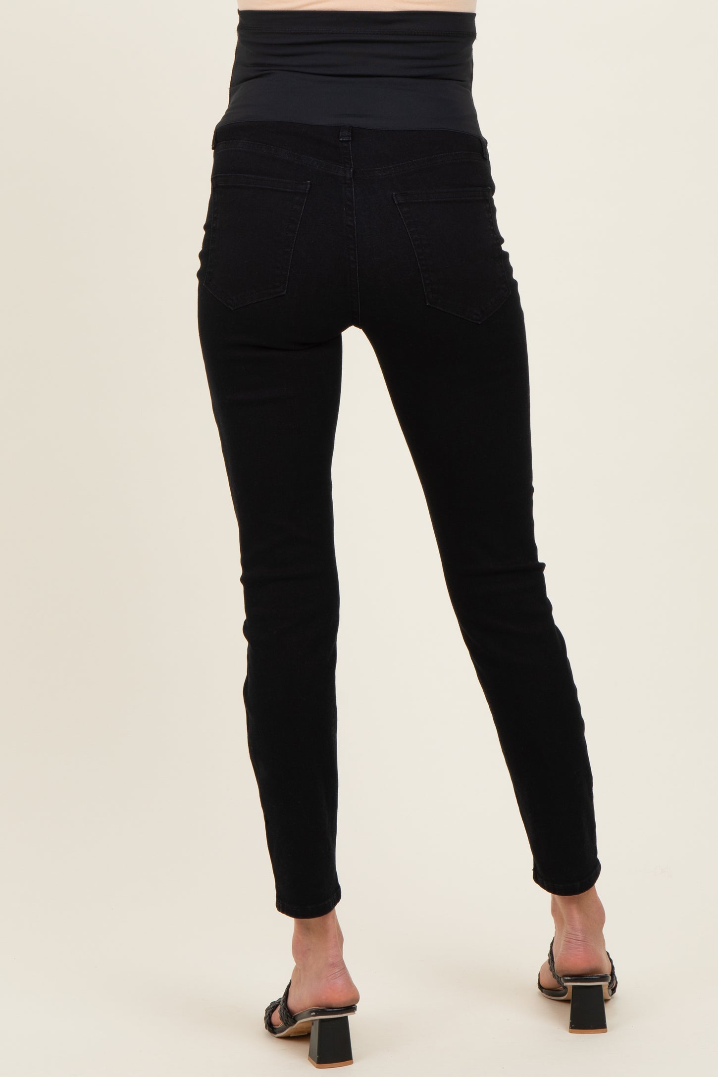 woman wearing black maternity skinny jeans with a high waistband and a fitted silhouette, showing the back view