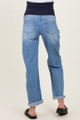 woman wearing light blue maternity jeans with a dark waistband, seen from the back, with a relaxed fit and rolled cuffs