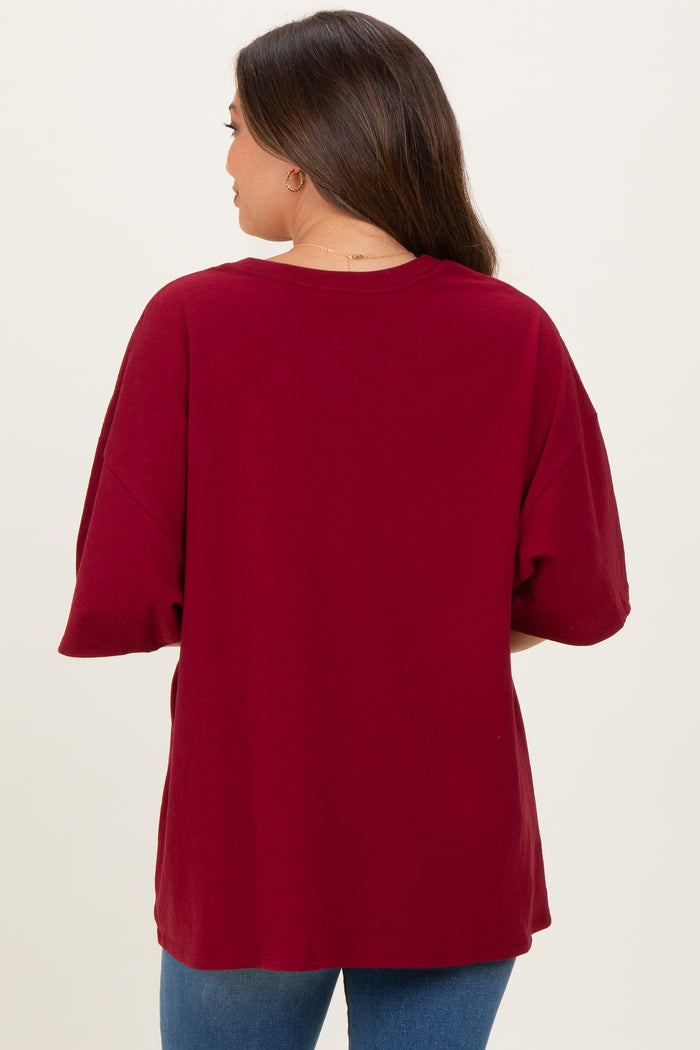 woman wearing a burgundy oversized maternity top, showing the back view