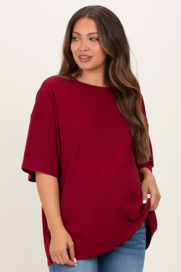 woman wearing a burgundy oversized maternity t-shirt with short sleeves and relaxed fit