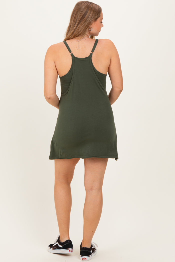 woman wearing a dark green maternity dress with adjustable straps, showing a relaxed fit and knee-length style from the back