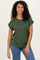 woman wearing a dark green short sleeve top and blue jeans, smiling at the camera