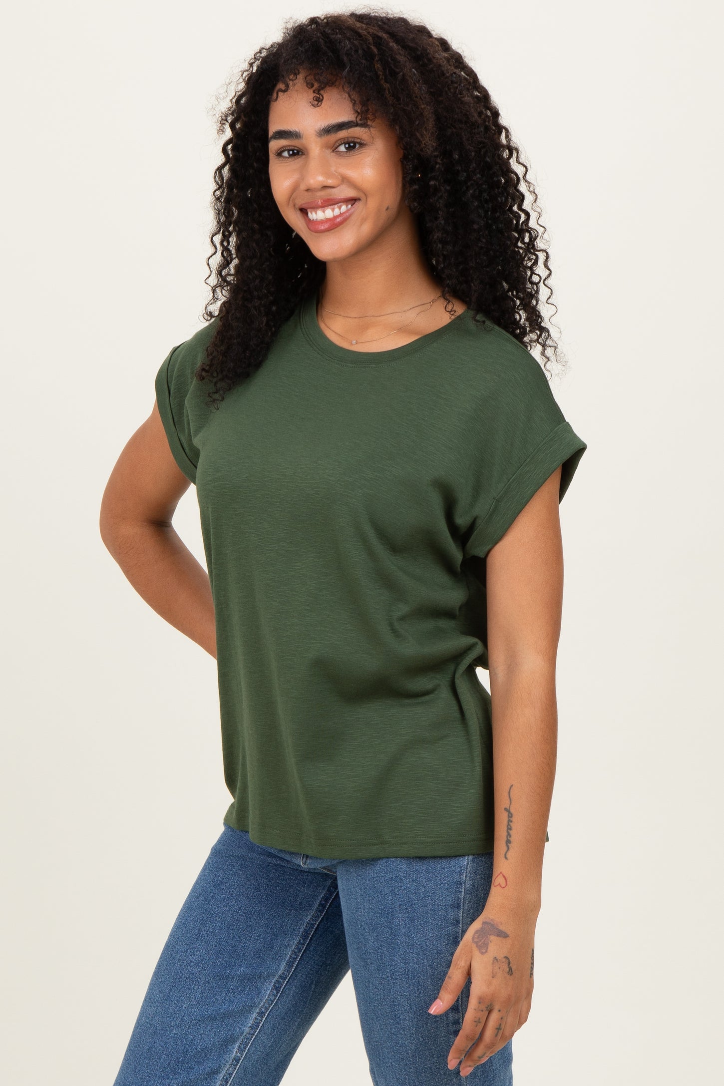 woman wearing a green short sleeve relaxed fit t-shirt paired with blue jeans