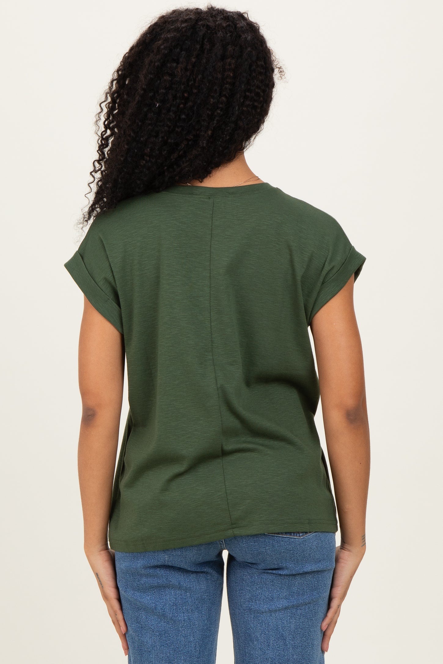 woman wearing a dark green short sleeve top with rolled cuffs and a relaxed fit, seen from the back