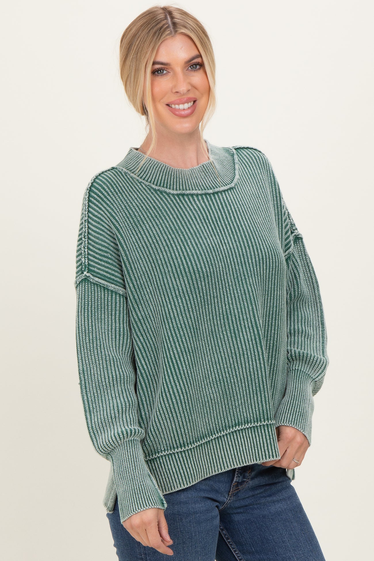 woman wearing a green striped oversized sweater and blue jeans