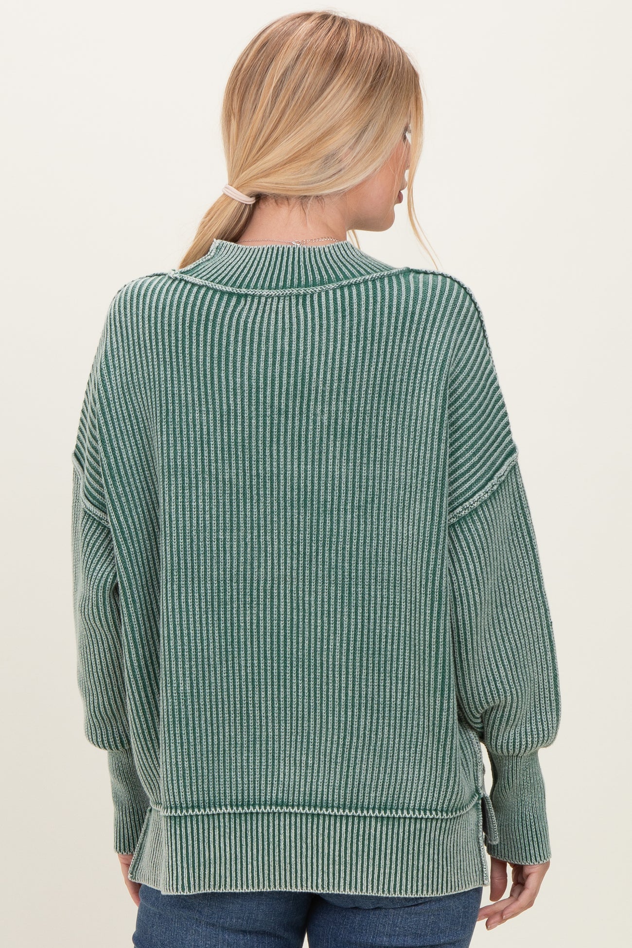 woman wearing a green striped oversized sweater with long sleeves and a relaxed fit, viewed from the back
