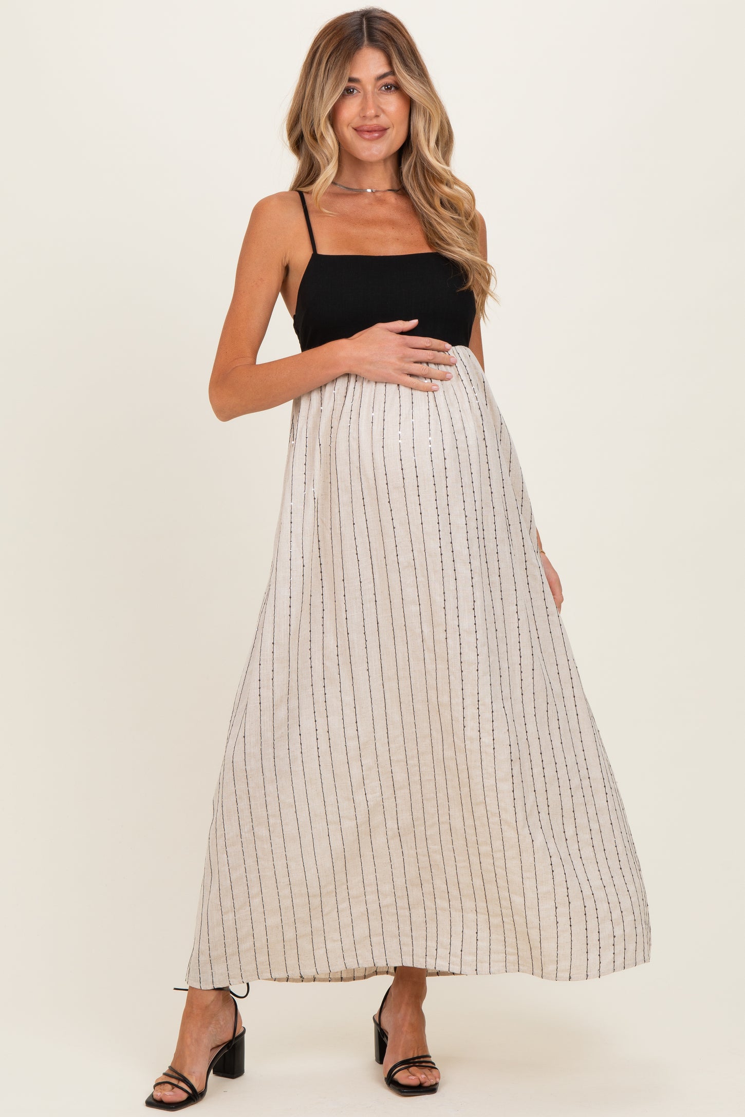 woman wearing a black and white striped maternity maxi dress and holding her baby bump