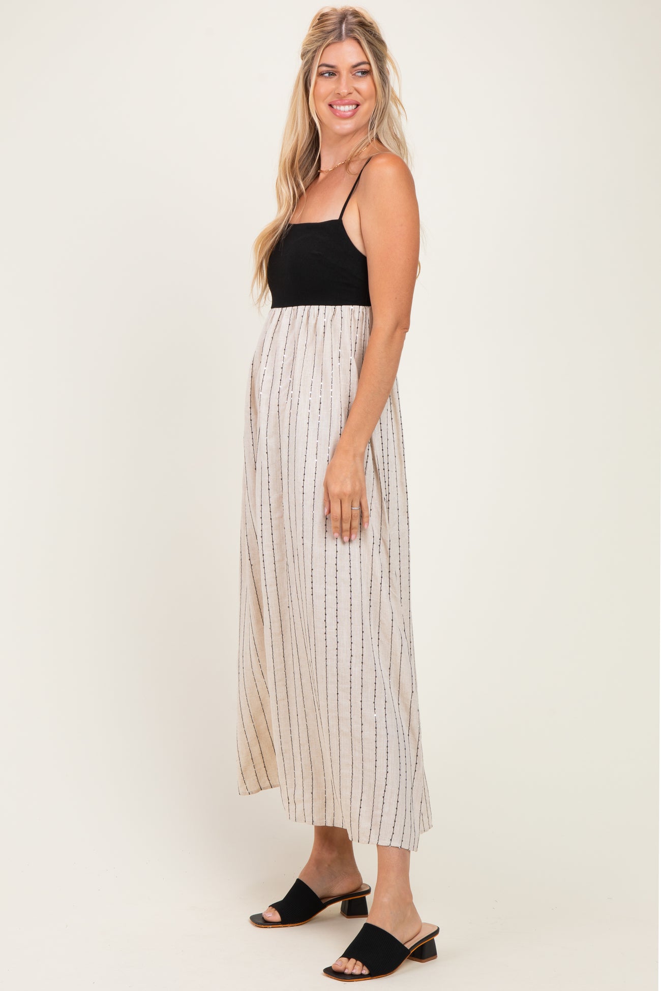 woman wearing a black and beige striped maxi dress with spaghetti straps and a flowy skirt