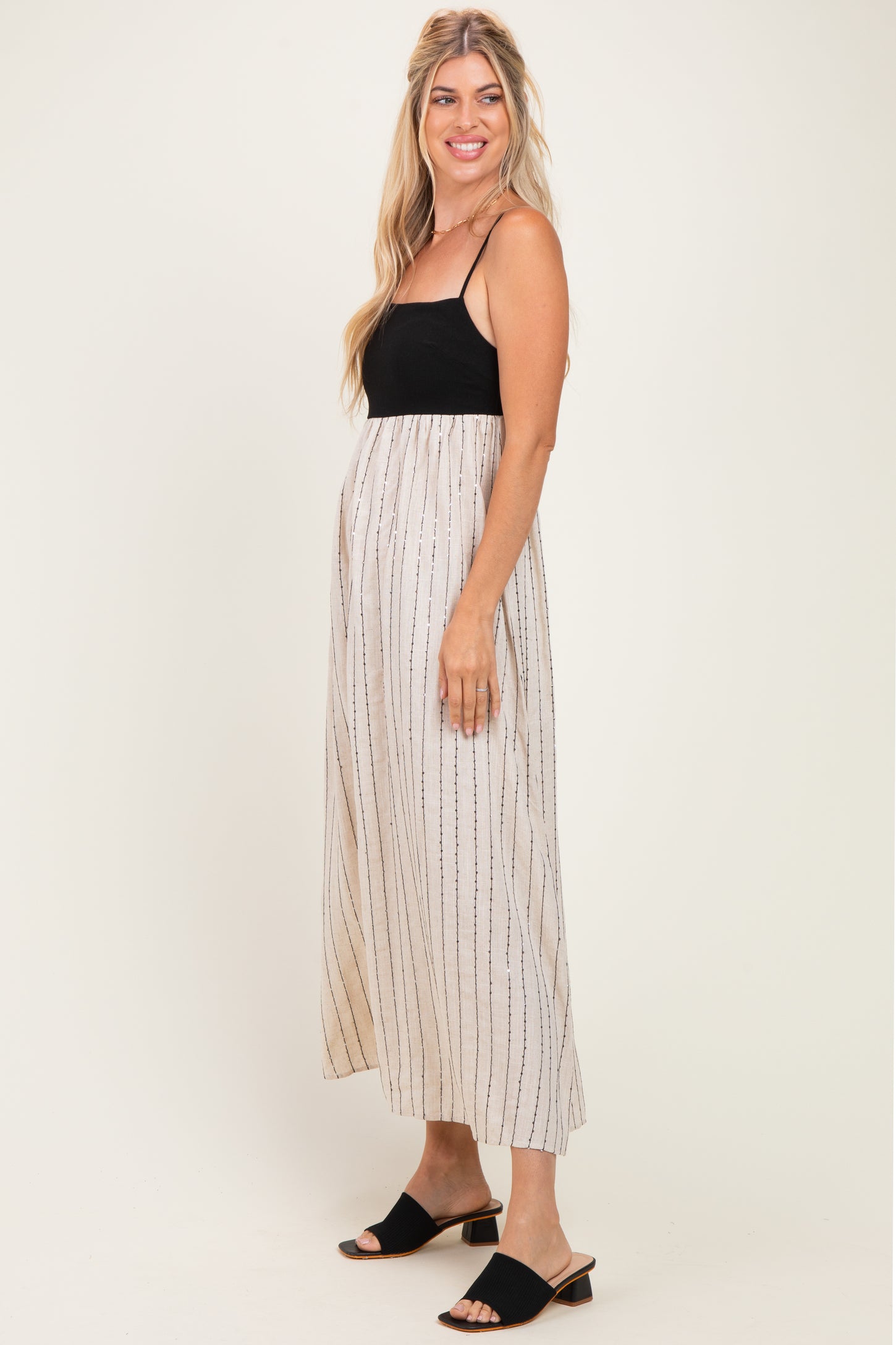 woman wearing a black and beige striped maxi dress with spaghetti straps and a flowy skirt