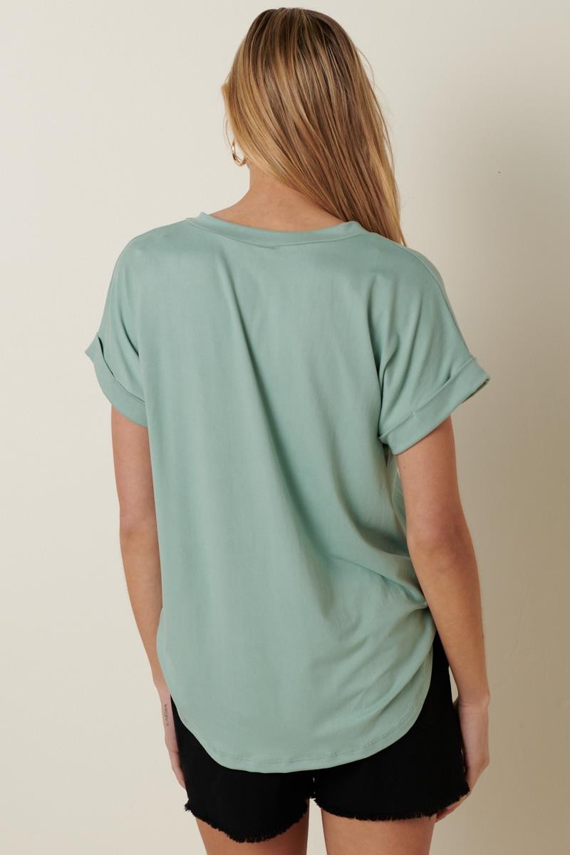 woman wearing a mint green short sleeve top with rolled sleeves and a relaxed fit, shown from the back