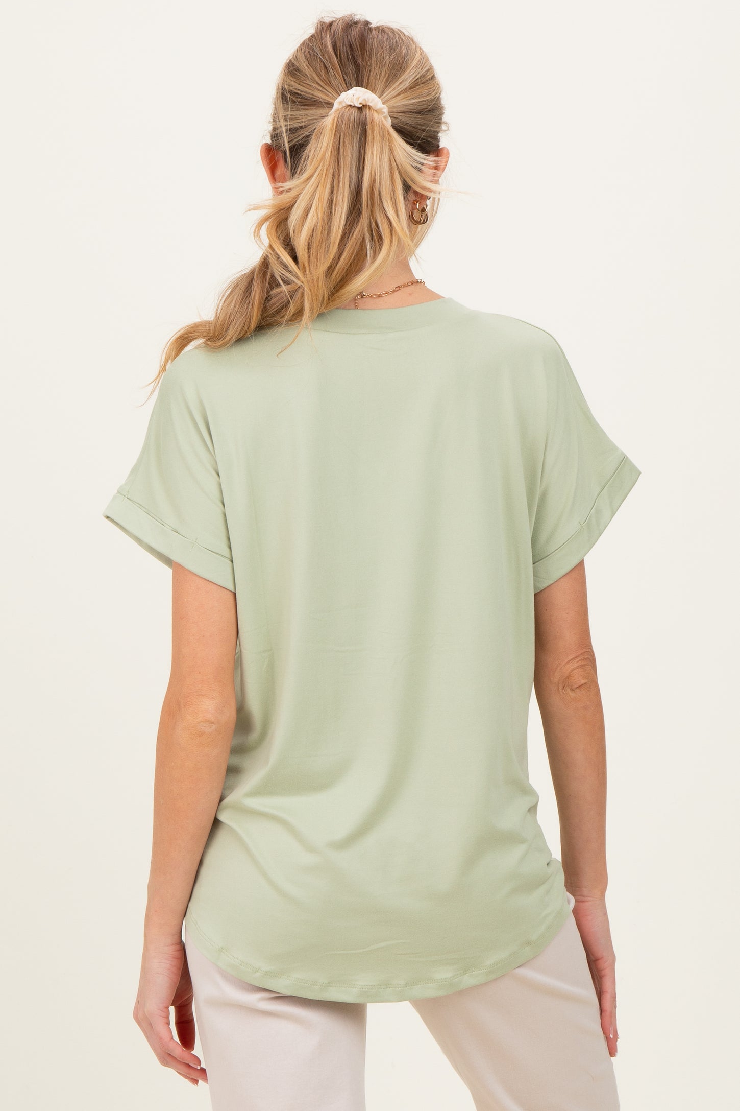 woman wearing a light green short sleeve maternity top, seen from the back
