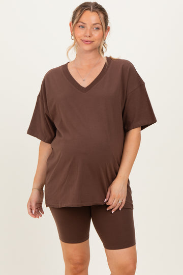 woman wearing a brown v-neck maternity tee and brown bike shorts, showing her baby bump