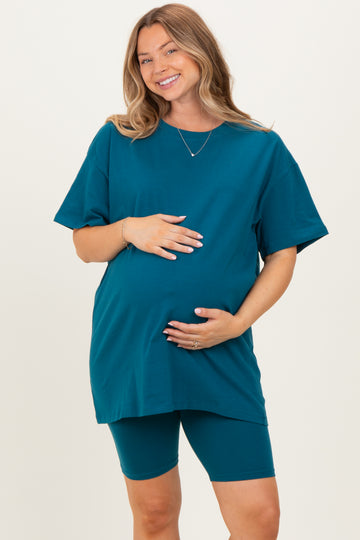 woman wearing a teal maternity t-shirt and matching bike shorts, holding her baby bump