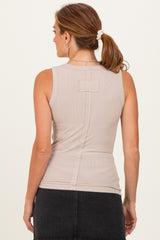 woman wearing a beige sleeveless top with a fitted silhouette and back detail