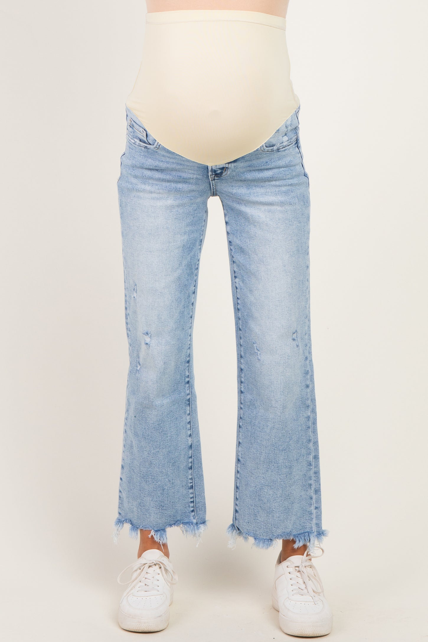 woman wearing light blue maternity flared jeans with a raw hem and a beige over-the-bump waistband