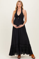 woman wearing a black halter maxi maternity dress and holding her baby bump