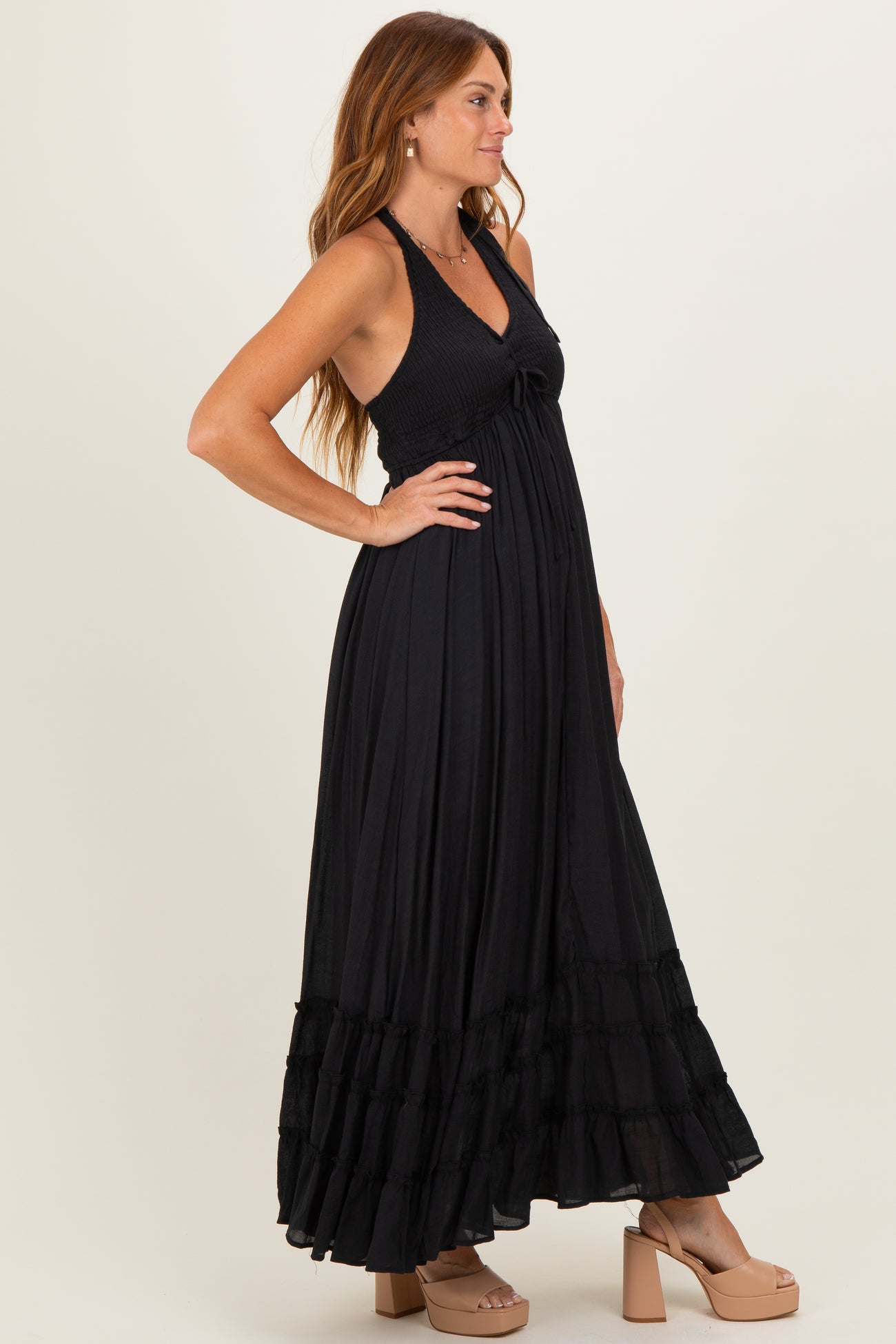 woman wearing a black halter maxi dress with tiered ruffle hem and strappy heels