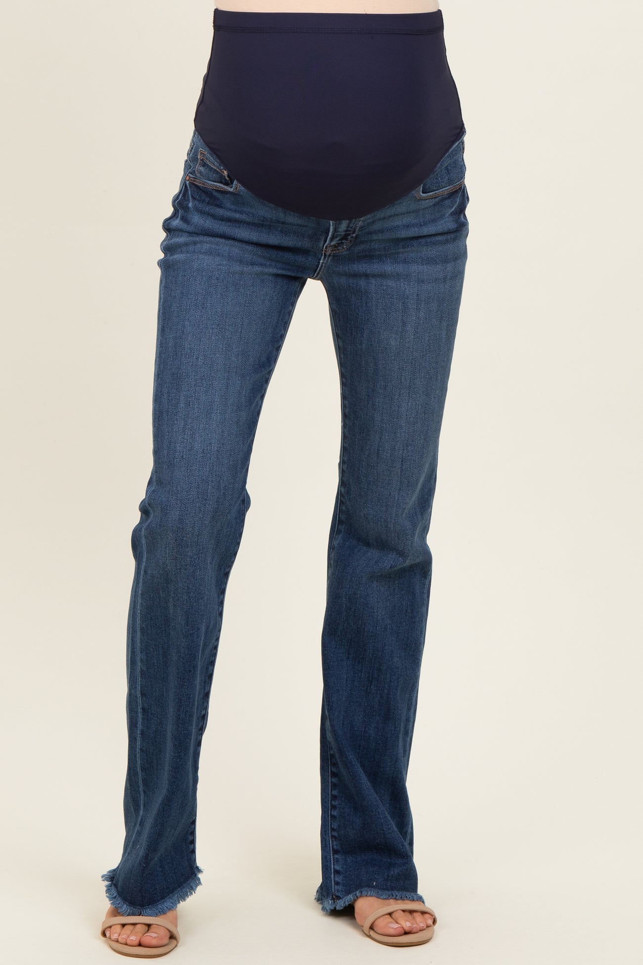 woman wearing dark blue maternity jeans with a stretchy waistband and frayed hem details