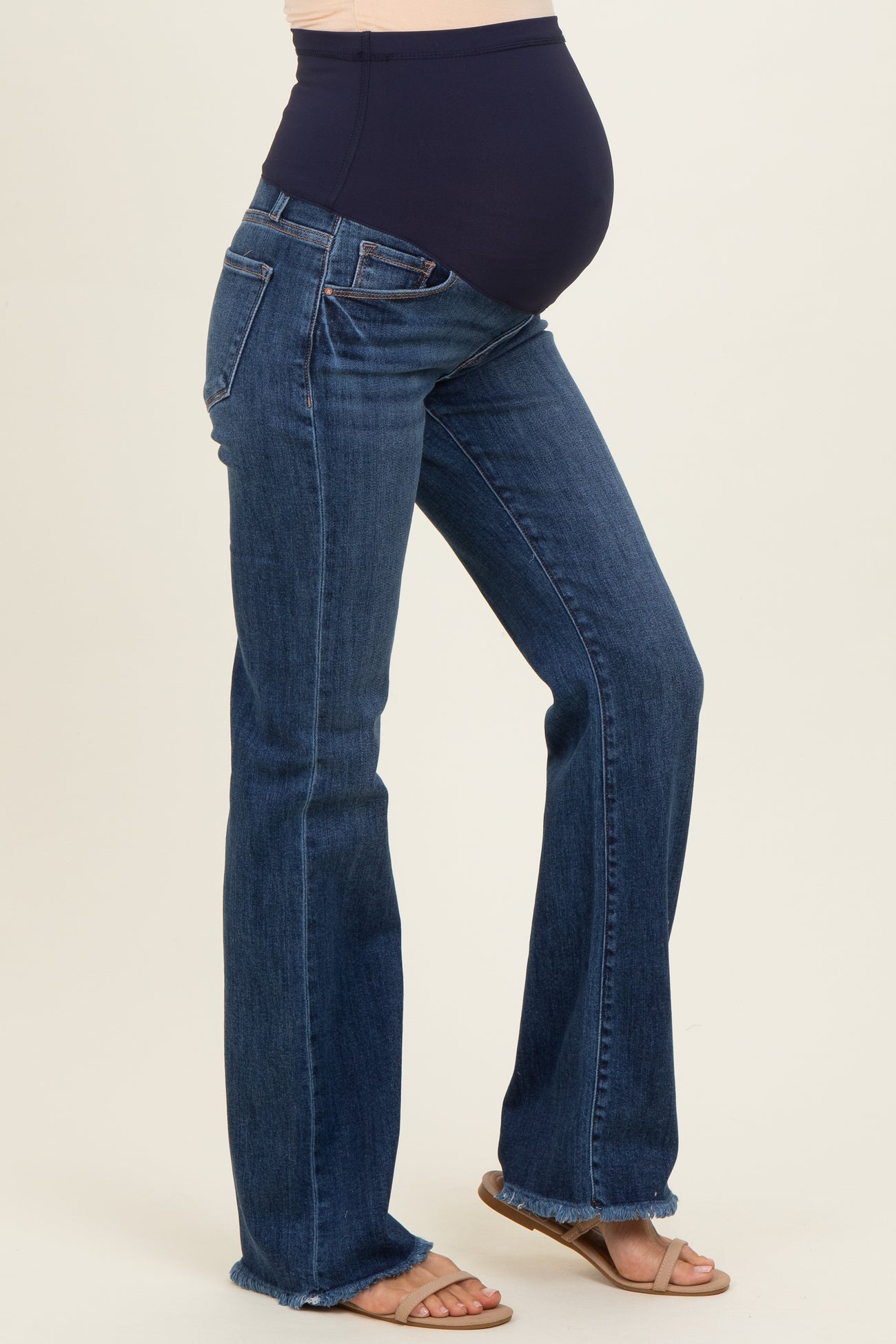 woman wearing a navy blue maternity belly band flared jeans, highlighting her baby bump